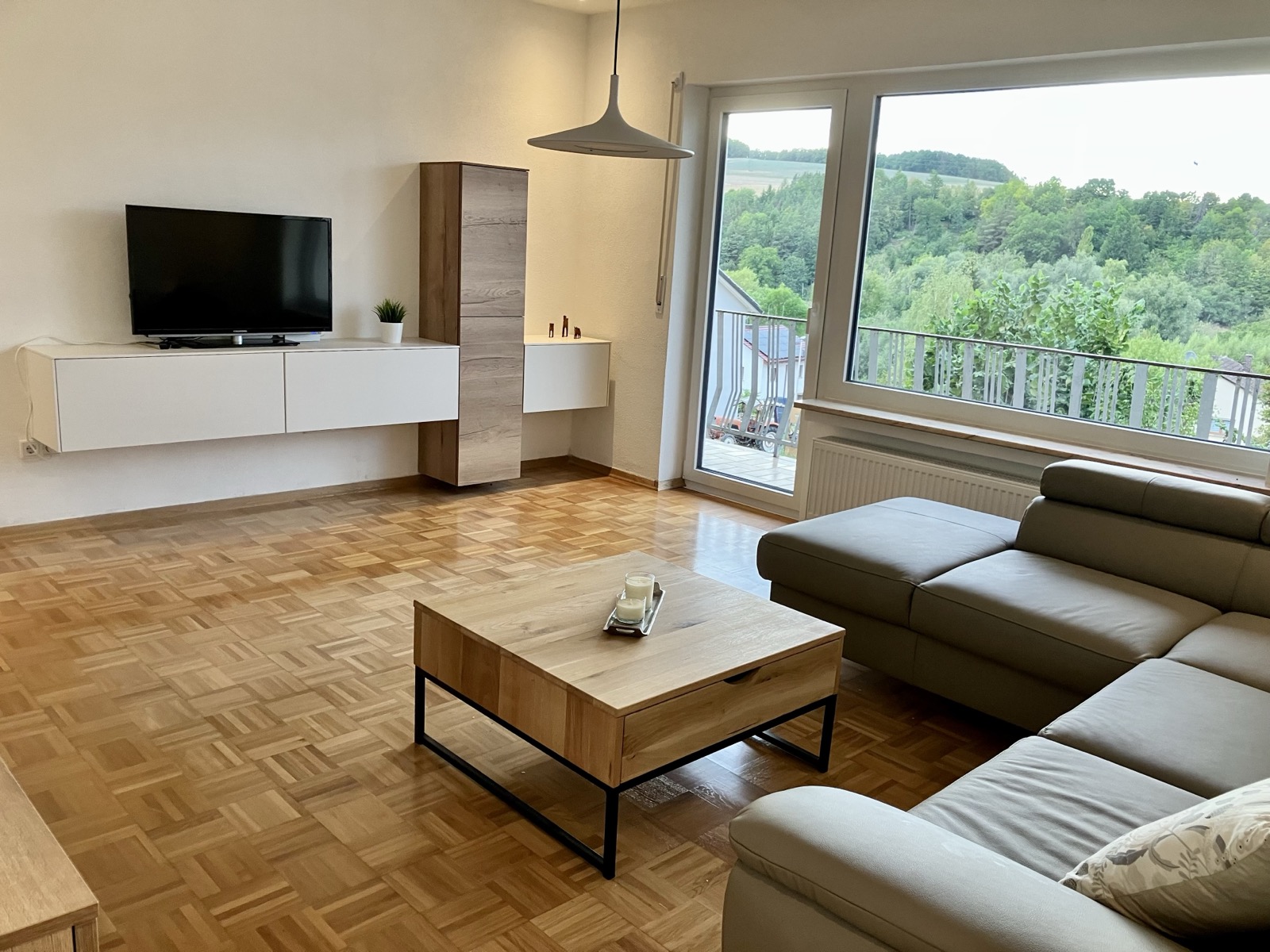 Wohnzimmer mit Smart-TV, Balkonzugang und Blick ins Grüne im Ferienhaus Obersfeld